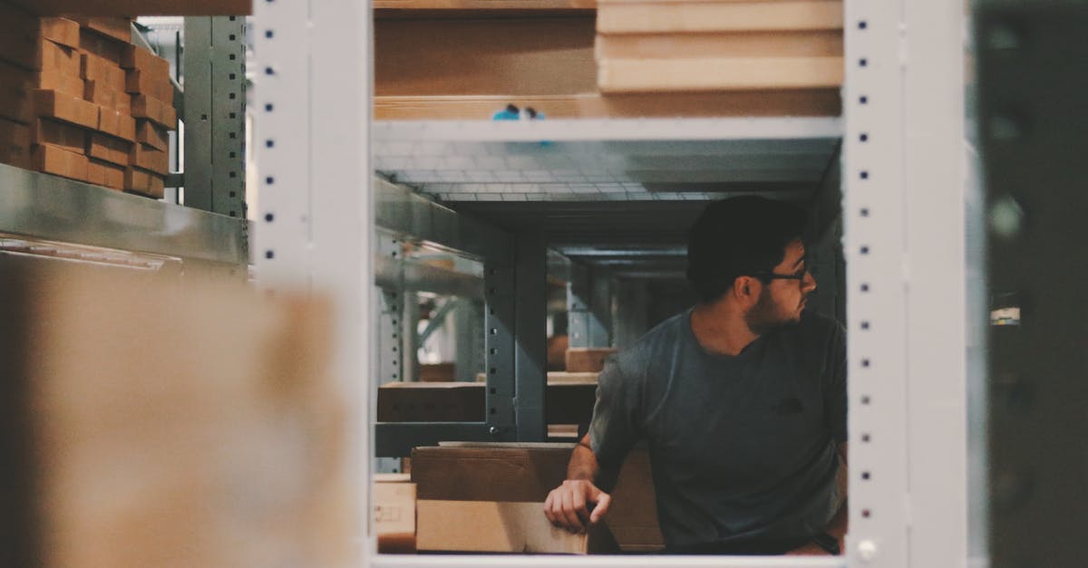 Man organizing wooden planks on warehouse shelves, creating an efficient storage solution.