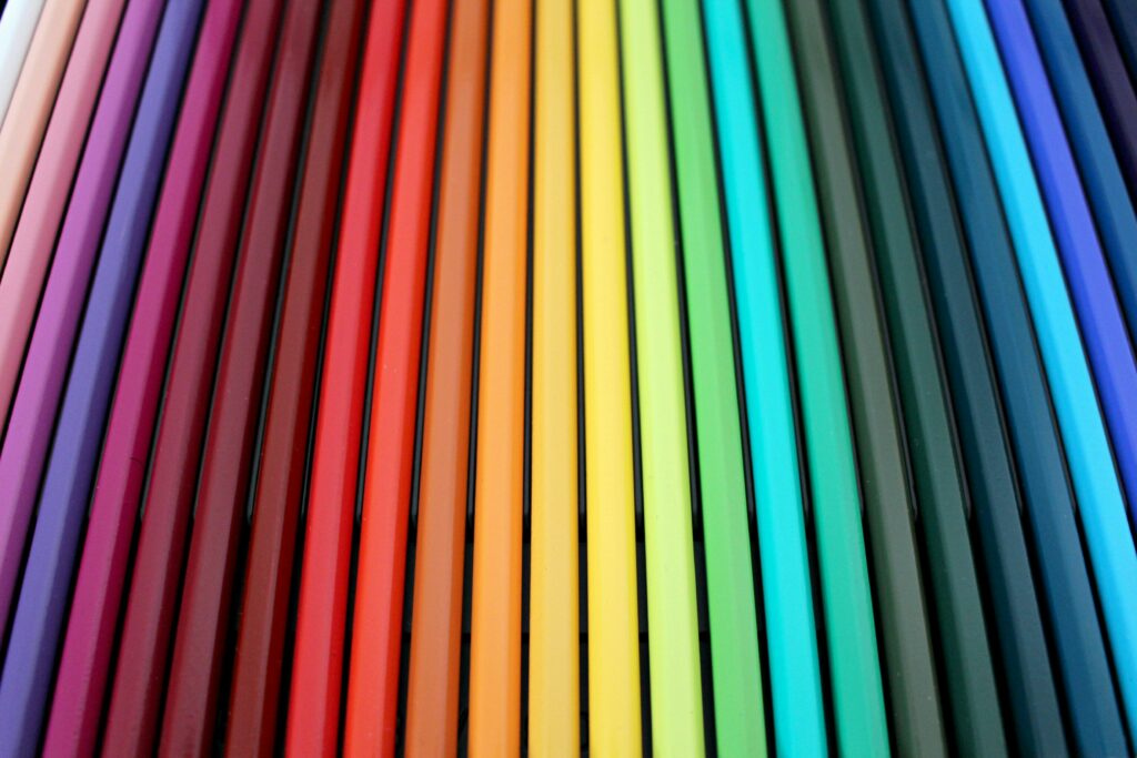 A vibrant and colorful arrangement of colored pencils forming a rainbow spectrum pattern.