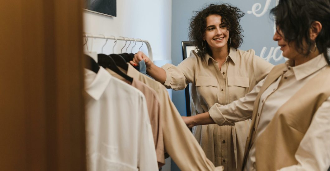 Two women enjoying a shopping experience in a modern fashion boutique, laughing and smiling.